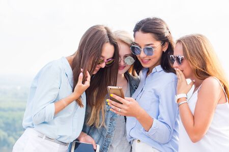Use of smartphones, the Internet, applications and messages. A group of beautiful girls look at the...