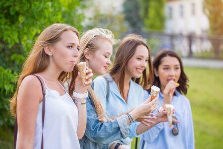 Beautiful young student girl eating ice cream in Park on nature backgroundの写真素材
