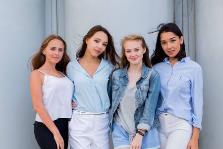 Fashion portrait of four beautiful attractive young women on the street. Cheerful smiling student girls looking at the camera. Lifestyle, youth, people, friendship conceptの写真素材