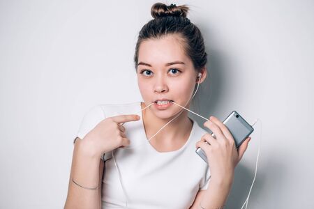 A young woman listening to music on a white backgroundの写真素材