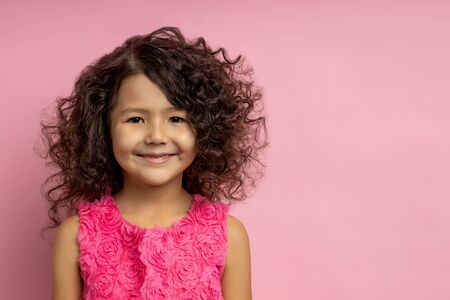 Closeup portrait of beautiful cheerful curly dark haired little girl, with brown eyes, happily...