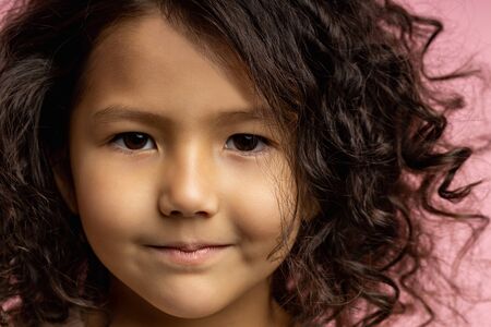 Closeup cropped headshot of lovely kid, little girl with dark curly hair, brown skin, brown eyes,...