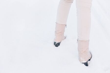 Close-up of women's feet in boots on white snow in winterの写真素材