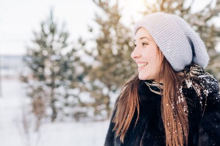 Closeup sideways portrait of a smiling happy woman on a winter background with copy space