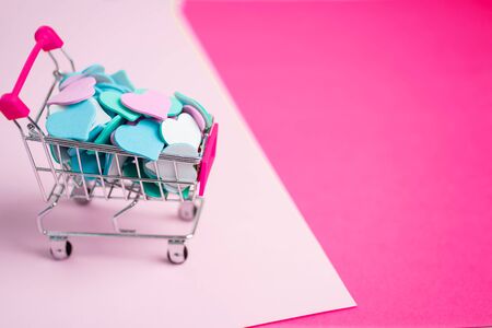 Valentine's day, spring, love, discounts and promotions, online shopping concept. Beautiful pink background with copy space and a small cart with heartsの写真素材