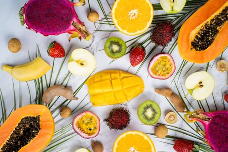 Exotic fruits and tropical leaves on tableの写真素材