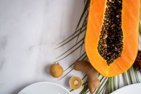 Exotic fruits and tropical leaves on table