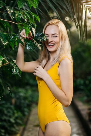 Woman in swimsuit on tropical plants backgroundの写真素材