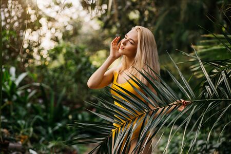 Woman in swimsuit on tropical plants backgroundの写真素材