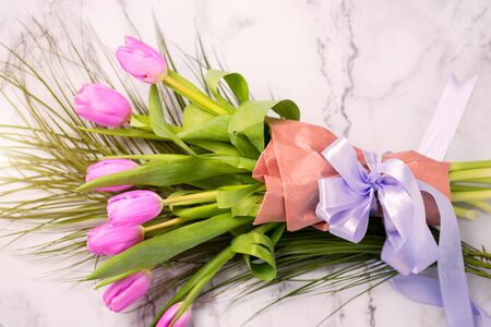 Closeup of a beautiful bright bouquet of pink red tulips on a white marble background. Spring, summer, flowers, conceptの写真素材