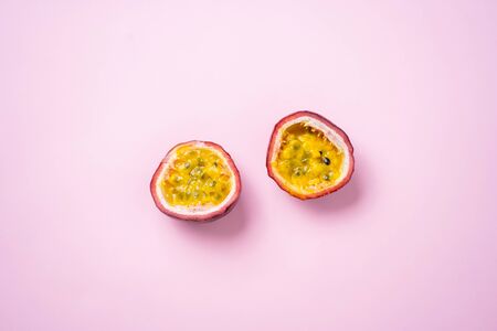 Two halves of passion fruit, maracuja isolated on pastel pink background with copy space. Selective focus. Exotic tropical fruits, food concept.の写真素材