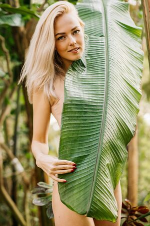 Woman in swimsuit on tropical plants backgroundの写真素材