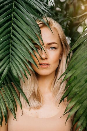 Woman in swimsuit on tropical plants backgroundの写真素材