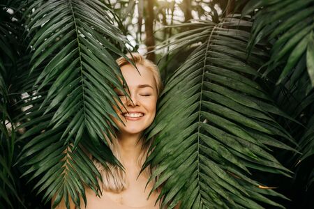 Woman in swimsuit on tropical plants backgroundの写真素材