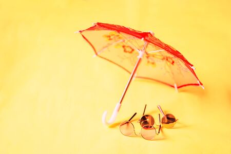 Sunglasses and umbrella isolated on yellow backgroundの写真素材