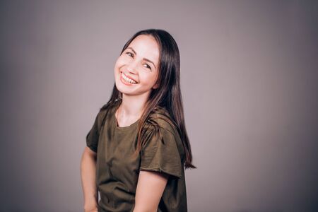 Positive human emotions. Headshot of happy emotional girl laughing from the bottom of her heart looking at the camera. Portrait of woman on grey backgroundの写真素材