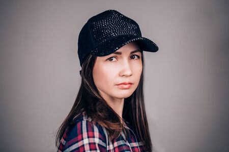 Portrait of beautiful woman on grey background looking at the camera. The girl wears a black capの写真素材