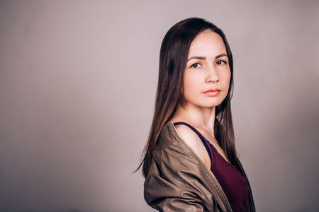 Portrait of beautiful young woman on grey background. Serious face, student girl. Closeup portraitの写真素材