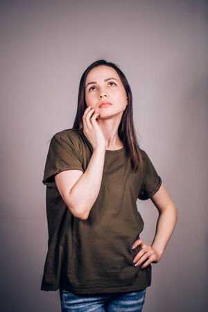 Thoughtful young brunette woman looking up, planning something in business, solving problems. Positive human emotions.の写真素材