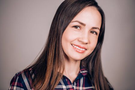 Happy joyful woman on grey background looking at camera with smile. Positive emotionsの写真素材