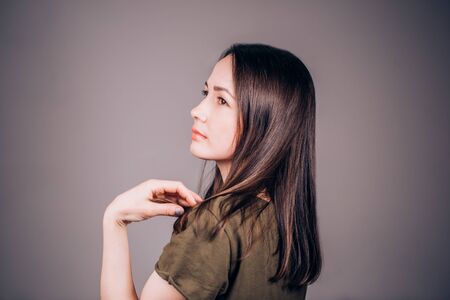 Beautiful young woman standing sideways on grey background, and laughs, smiles. The profile of the person, copy space.の写真素材