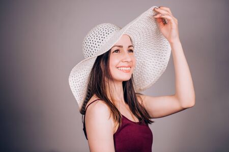 Happy young brunette woman in beige hat with joy and smile looking away. Summer, beach, sun conceptの写真素材