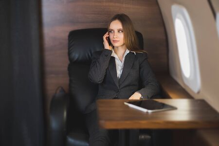 Beautiful rich woman in first class plane. Young businesswoman in formal wear sitting in private...