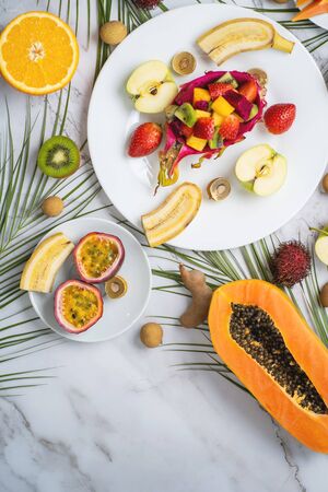 Healthy breakfast from tropical exotic ripe juicy fruits on plates on table. Delicious snack, travel, vacation, vitamins, summer concept. Top view, flat lay.の写真素材