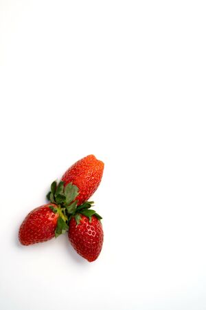 Three ripe fresh red strawberries with green leaves isolated on a white background.の写真素材