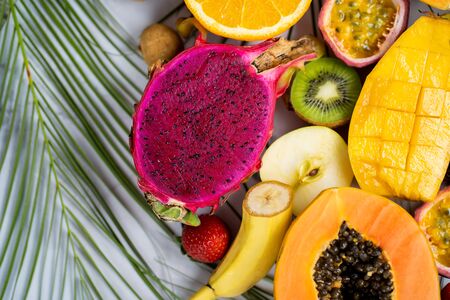 Exotic fruits and tropical leaves on tableの写真素材