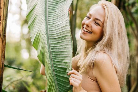 Woman in swimsuit on tropical plants backgroundの写真素材