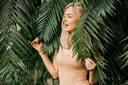 Woman in swimsuit on tropical plants backgroundの写真素材