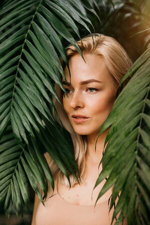 Woman in swimsuit on tropical plants backgroundの写真素材