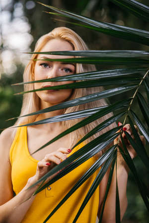Woman in swimsuit on tropical plants backgroundの写真素材