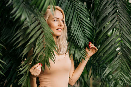 Woman in swimsuit on tropical plants background