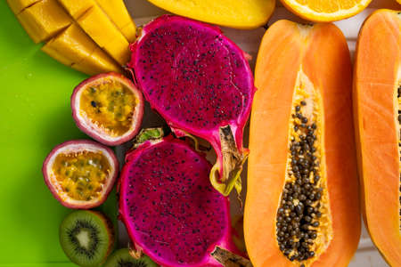 Assortment of sliced tropical exotic fruits on white tray. Top view. Close up. Healthy vegan breakfast of raw papaya, orange, mango, dragon fruit, kiwi, maracuja. Summer, food concept.の写真素材