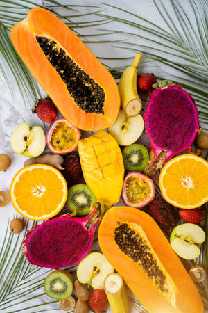 Group of exotic tropical fruits. Papaya, mango, dragon fruit, passion fruit, kiwi, strawberry, apple, banana, orange, longan, green leaves on white background Top view Flat layの写真素材