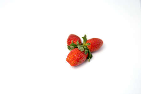 Three ripe fresh red strawberries with green leaves isolated on a white background.の写真素材