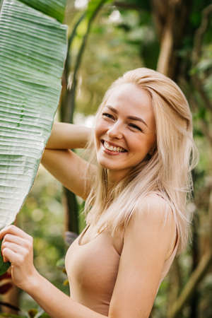 Woman in swimsuit on tropical plants backgroundの写真素材
