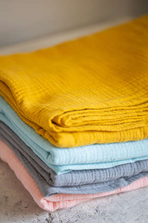Pink, blue, mustard, gray muslin fabrics, diapers on a white background closeup. Beautiful pile of fabrics on the tableの写真素材