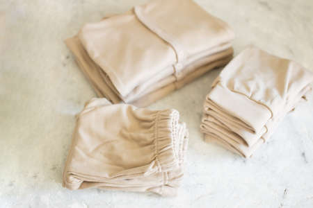 Beautiful beige Baby's clothes on white backgroundの写真素材