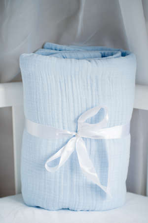 Beautiful blue Packed baby muslin blanket on the cot with a bow. Gift for a newborn babyの写真素材