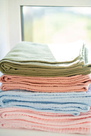 Colorful blankets on the windowsill in a stack, closeupの写真素材