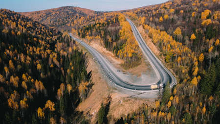 Sharp turn with cars, drone shooting autumn nature in the forestの写真素材