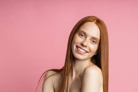 Youth, beauty, skin care concept. Joyful caucasian female model without makeup, with healthy long ginger hair, broadly smiling looking at camera with happy pleased expression.の写真素材