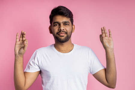 All right. Positive human facial expressions, emotions, body language concept. Carefree happy young indian man with stubble, showing Ok sign with both hands and smiling on pink background.の写真素材