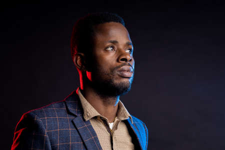 business man looking to the side copy space on black background with blue and red lights in Studioの写真素材