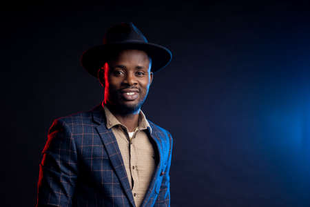portrait of smiling african businessman wearing shirt, checked suit, looking at camera, standing against black background.の写真素材