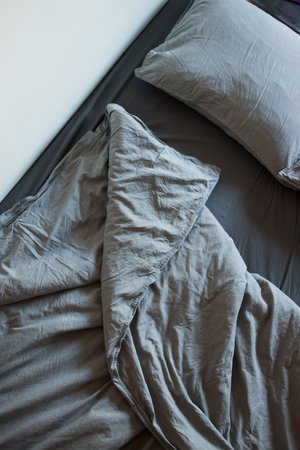 The view from the top of the morning gray bed after sleep. Blankets, sheets and pillowsの写真素材