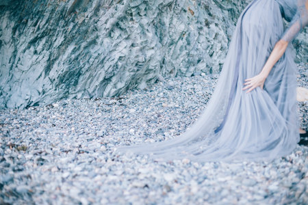 The focus of beautiful stones, rocks on the seashore, disfocus girl in a dress with the edge of the pictureの写真素材